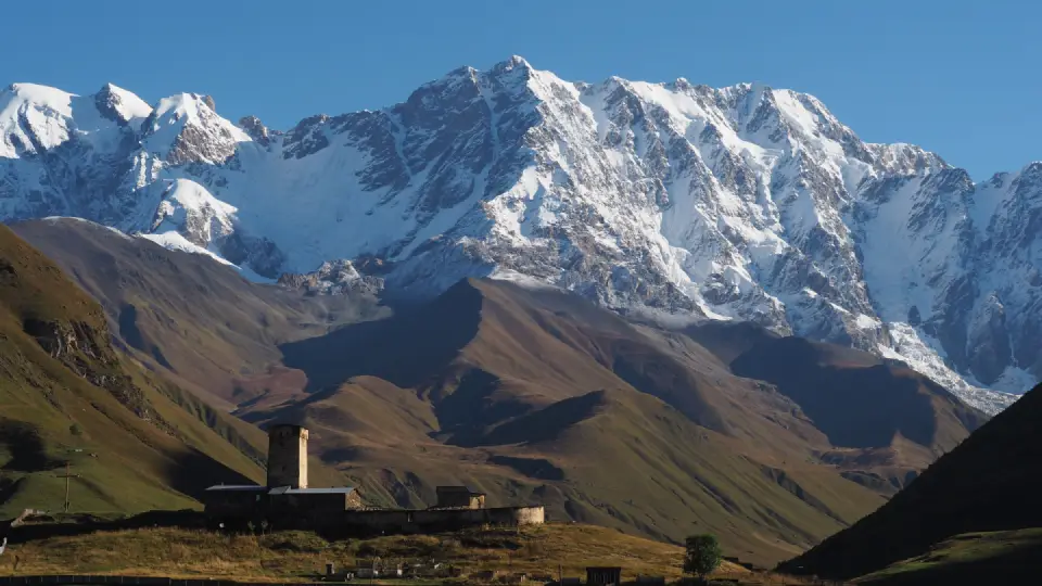 Snow-covered Caucasus mountain peaks rising above a dramatic alpine landscape in Georgia.