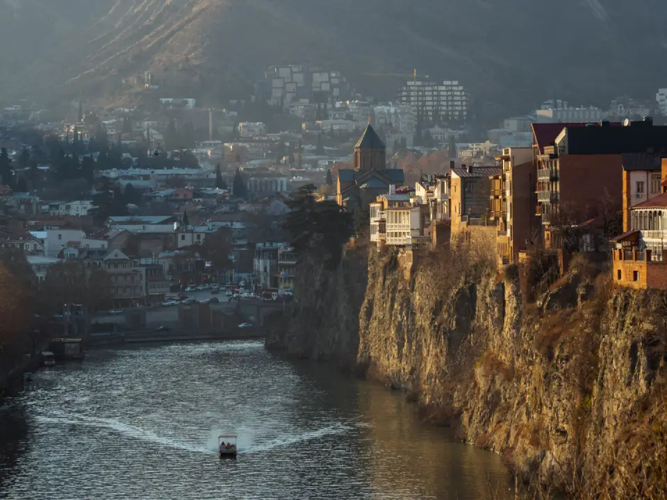 Historic buildings and ancient fortress structures overlooking a river in Georgia.